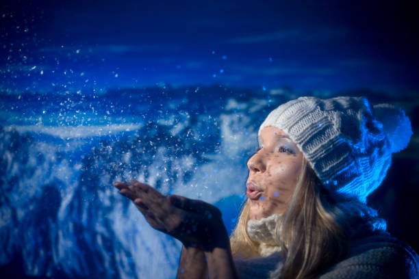 Young female blowing snow on her hands