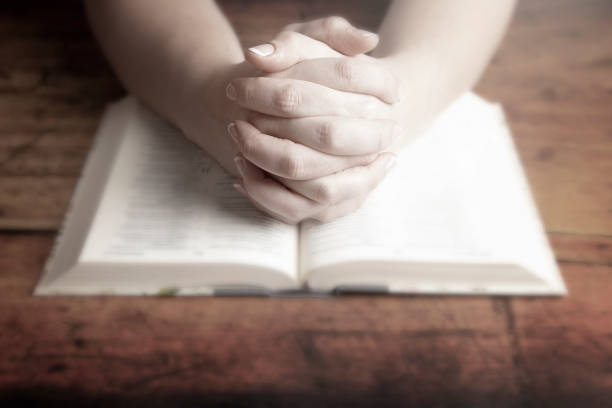 istock A Woman Praying with Her Hands Folded over Her Bible 1058831028