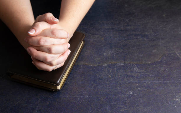 istock A Woman Praying with Her Hands Clasped on a Bible 1058831556