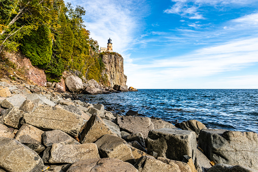 A boulder strewn beach leads to the cliff where Split Rock Lighthouse stands on the shores of Lake Superior in Northeastern Minnesota.