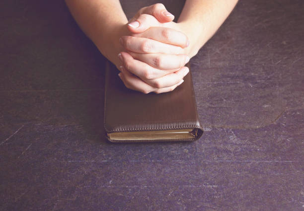 istock A Woman Praying with Her Hands Clasped on a Bible 1058832668