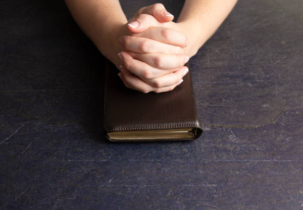 istock A Woman Praying with Her Hands Clasped on a Bible 1058832850