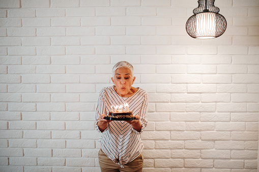 Senior woman blowing birthday candles