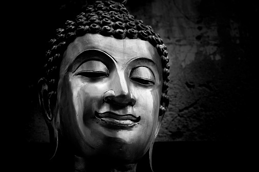 A black and white smiling portrait of the Buddha
