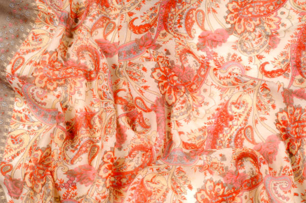 istock Texture, pattern, background. Silk fabric - paisley on a beige background. This beautiful silk border print has paisley and floral print in orange and grey on a natural colored background. 1058843304