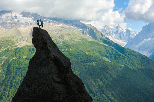 Two climbers giving high five on top of a mountain pinnacle