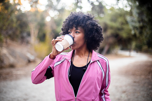 A young black woman walking with a cup of coffee