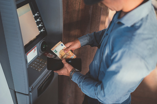 Empresario en el cajero automático de retiro de dinero, billetes falsos de cincuenta euros photo