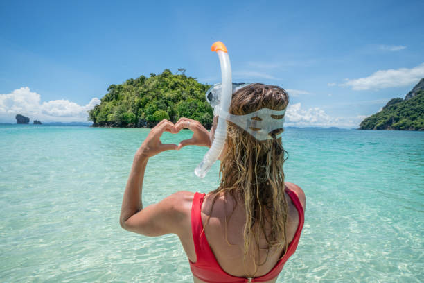 istock Woman making heart shape frame on tropical beach landscape 1058857028