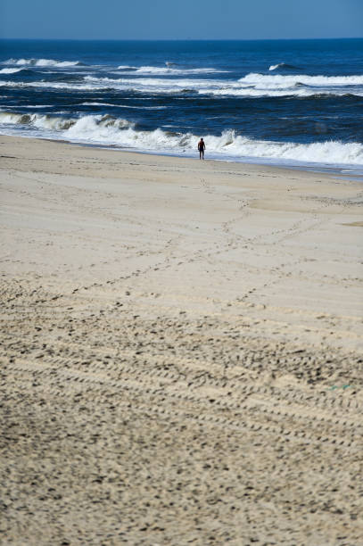 istock Man walking barefoot making footprints in the sand on a beach 1058857068