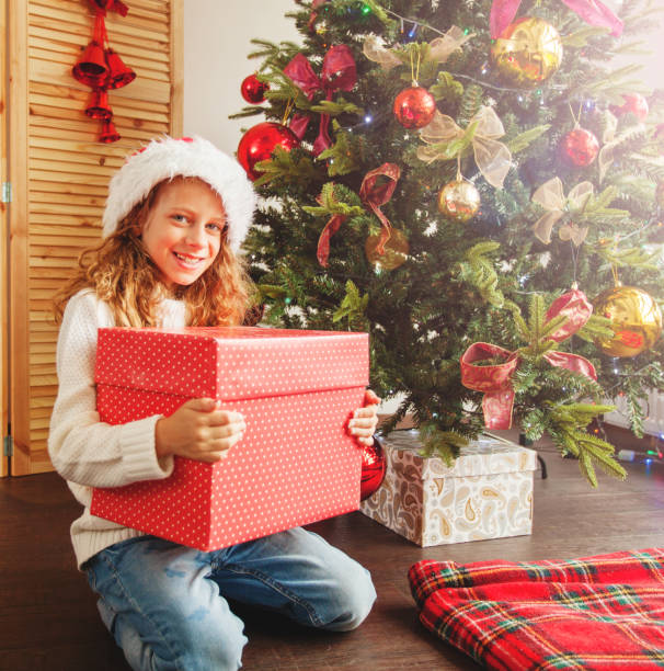 istock Child with gift near christmas tree 1058868300