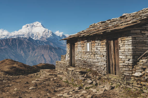 A view of an old stone stable on the Khopra Ridge looking towards Dhaulagiri I in the Nepal Himalayas on a clear sunny day.