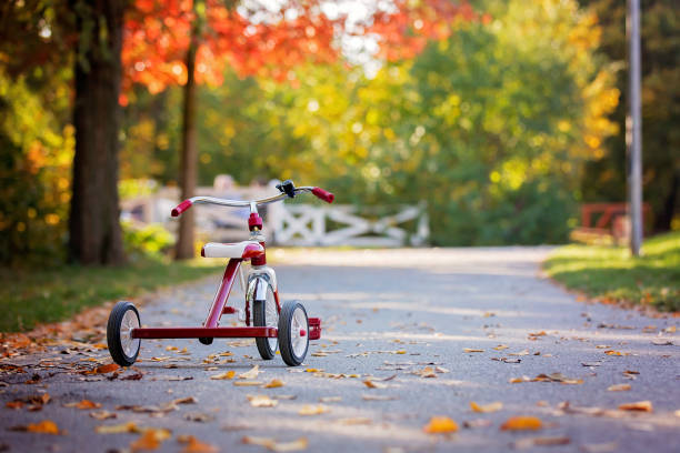 tricycle dans le parc à l’heure du coucher du soleil, automne, enfants dans le parc - tricycle photos et images de collection