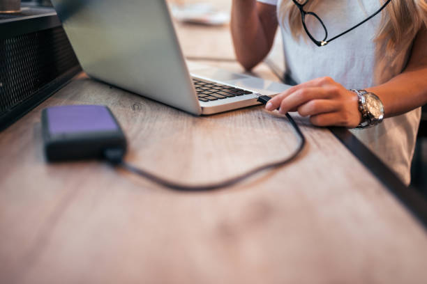 Close-up image of a woman freelancer connecting an external hard drive to the laptop. Close-up image of a woman freelancer connecting an external hard drive to the laptop. hard drive photos stock pictures, royalty-free photos & images