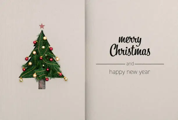 Photo of Merry Christmas and happy new year greetings in vertical top view cardboard with natural eco decorated christmas tree pine.Ecology concept.Xmas winter holiday season social media card background