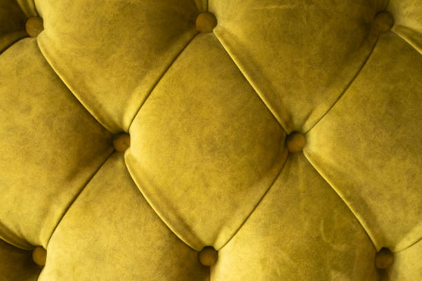 Green velvet capitone textile background, retro Chesterfield style checkered soft tufted fabric furniture diamond pattern decoration with buttons, close up.