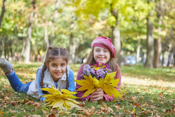 Ragazza con sindrome di Down e bambina nel parco autunnale. - foto stock