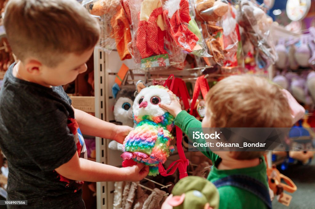 Two cute baby boys walking together in mall. Pair of kid friends holding hands during walk Two cute baby boys walking together in mall. Pair of kid friends holding hands during walk. Toy Store Stock Photo