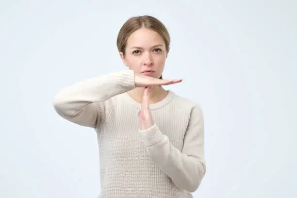 Closeup portrait of young woman showing time out gesture with hands isolated on gray wall background. Negative human emotion facial expressions, feeling body language reaction, attitude