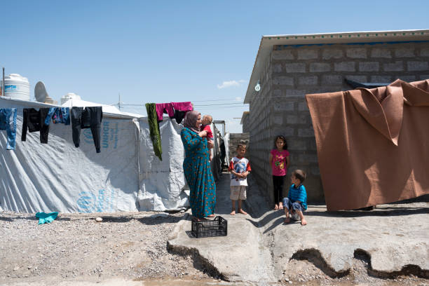 Syrian Kurdish refugees living in Iraq A mother and several children stand beside a clothesline outside a home in Darashakran refugee camp, located in northern Iraq. The camp is home to several thousand Syrian Kurds who fled fighting in Syria. (May 8, 2017) iraqi kurdistan stock pictures, royalty-free photos & images
