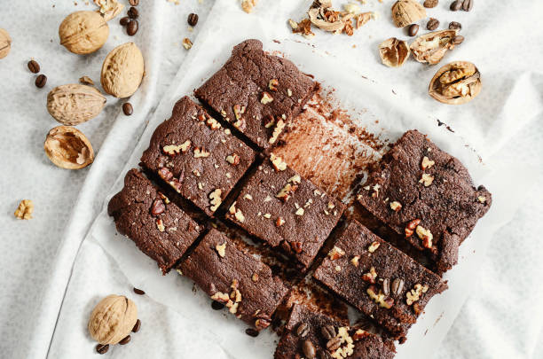 istock A batch of chocolate brownies with nuts cut into pieces on white background. Directly above, overhead shot. 1058915232