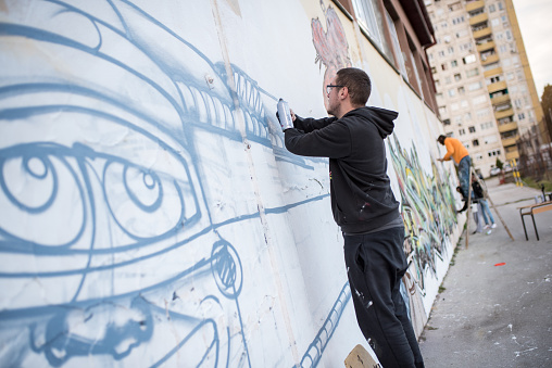 young artists draw murals on the wall