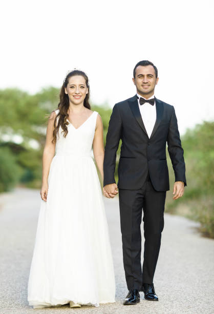 Bride and grrom holding hands  looking to camera ,outside shot.