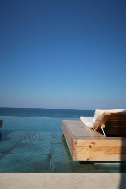 istock Pool lounger on infinity pool with clear blue background 1058927950