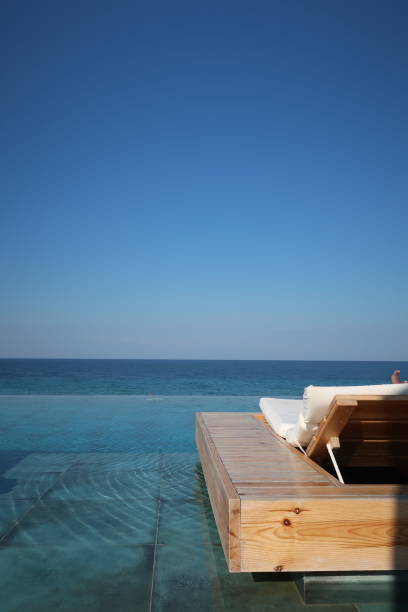 istock Pool lounger on infinity pool with clear blue background 1058928114