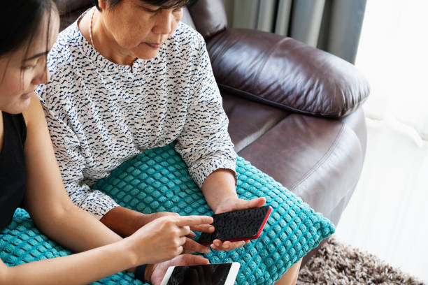 Adult woman and daughter using smartphone with blank screen. Woman pointing on mobile phone display Adult woman and daughter using smartphone with blank screen. Woman pointing on mobile phone display teenager couple child blond hair stock pictures, royalty-free photos & images