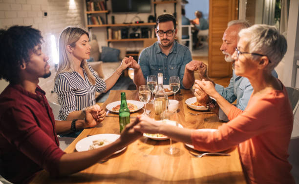 istock Family and guests praying before lunch 1058930372