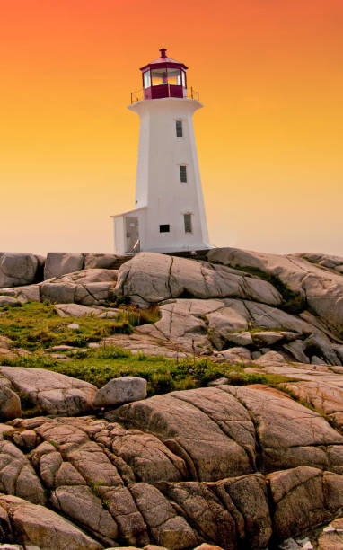 istock Scenic lighthouse at sunset with boulders in foreground and blue sky 1058935558