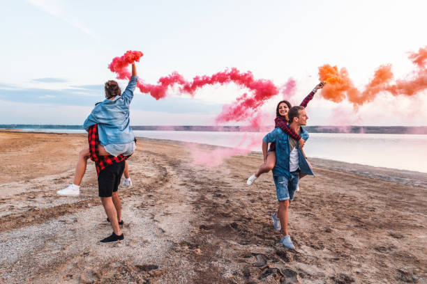 istock young friends running with hand flare or fusee 1058937176