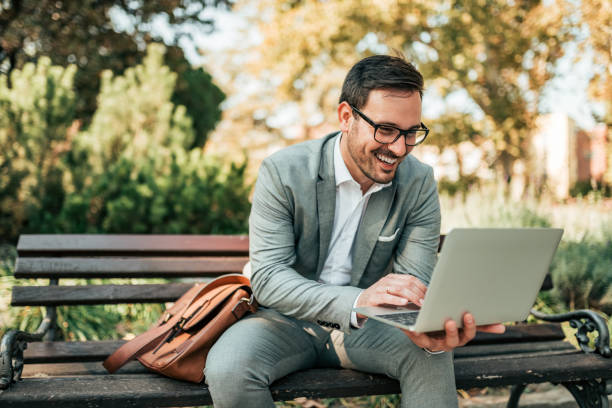 istock Handsome businessman using laptop in the park. 1058944292