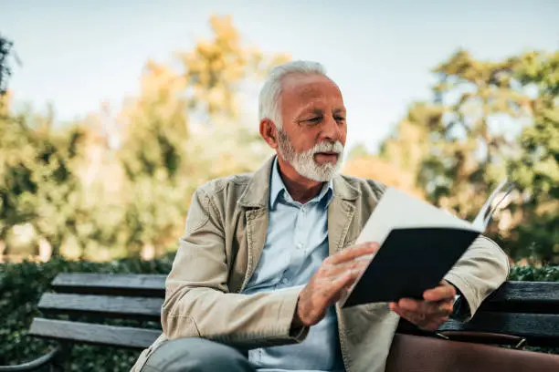 Photo of Charming old man reading a book.