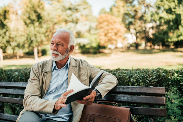 istock Handsome mature man reading book outdoors. 1058945254