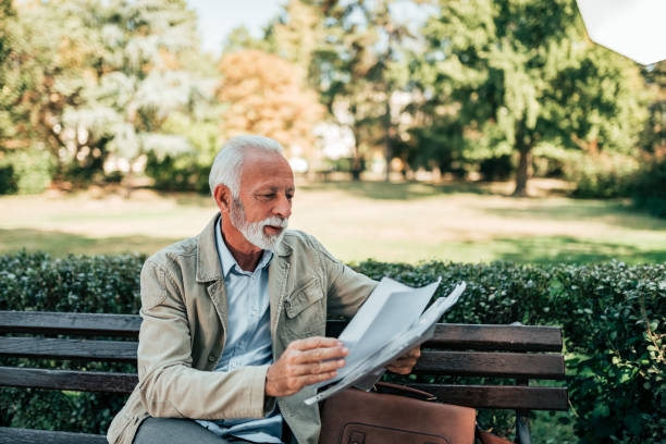 istock Retired man reading newspapers in the park. 1058945258