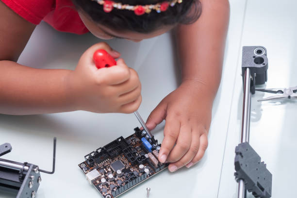 little hands of a smart kid working on electronic device with a screw driver on hand and other components for summer camp - child prodigy imagens e fotografias de stock