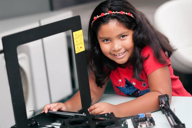 menina aprendendo e trabalhando as mãos, construindo uma impressora 3d com peças montadas na mesa - child prodigy - fotografias e filmes do acervo