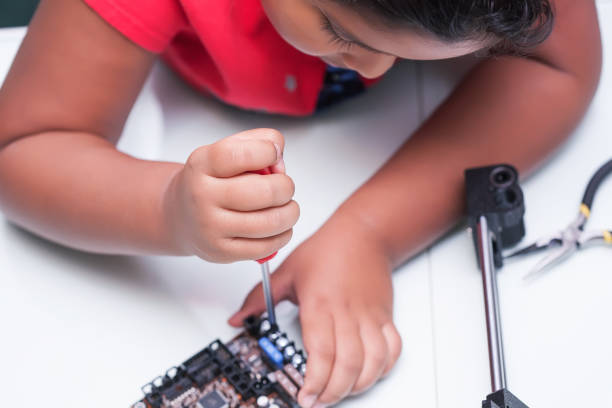 young child learning about electronics and technology by wiring and holding screw driver making a connection in class - child prodigy imagens e fotografias de stock