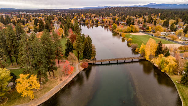 guardando giù su mirror pond sul fiume deschutes a bend oregon fiancheggiato da alberi colorati autunnali - oregon foto e immagini stock