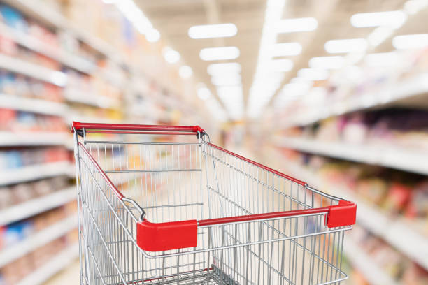 istock Supermarket aisle blurred background with empty red shopping cart 1058986040