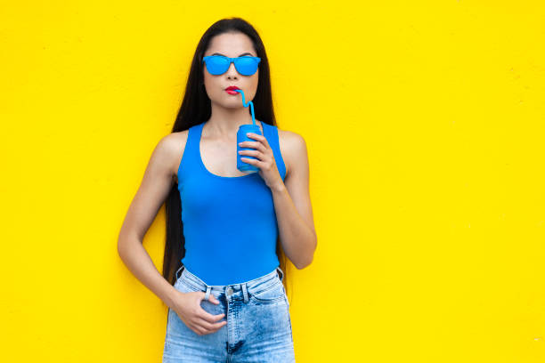 istock Woman in blue outfit drinking from blue can 1058986420