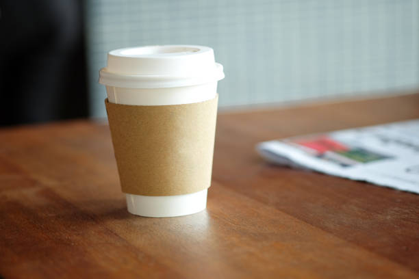 Coffee paper cup and newspaper on wood table.