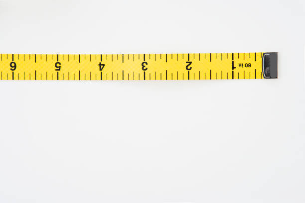 Yellow measuring tape curls on a white background isolated. Tailor's sewing  cloth measuring tool. Ruler for body measuring. Stock Photo