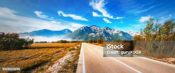 Highway Through A Desert Landscape With Mountains In Background Stock Photo - Download Image Now