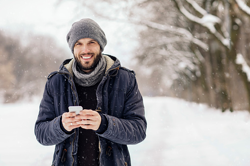 Young man using smartphone on snowy day