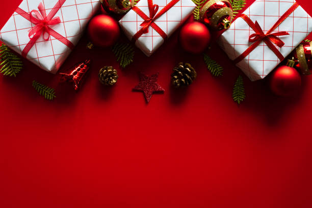 istock Christmas background concept. Christmas gift box with red ball and pine cones on red background. 1059007964