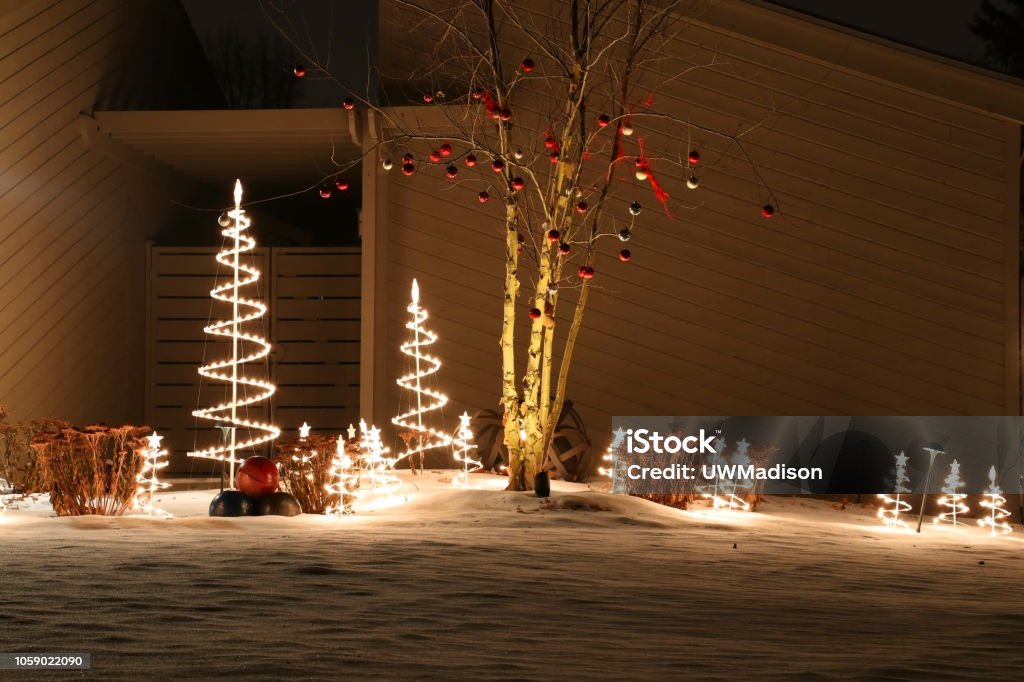 Winter holidays outdoor decoration background. Snowy night scene with front yard of the house decorated by glowing in the dark garlands. Christmas and New Year holiday background. Christmas Stock Photo