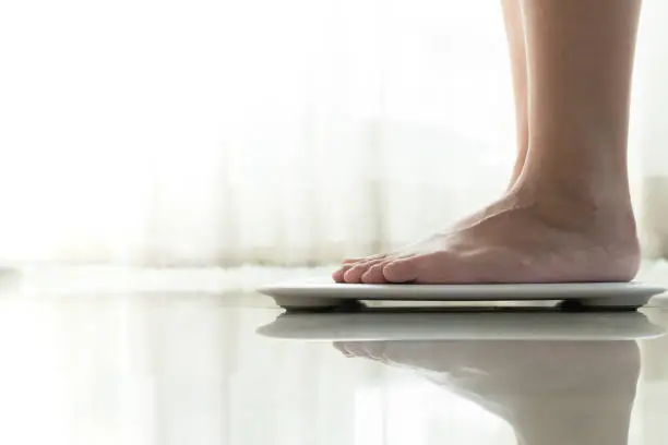 Photo of young woman standing on digital weight scale